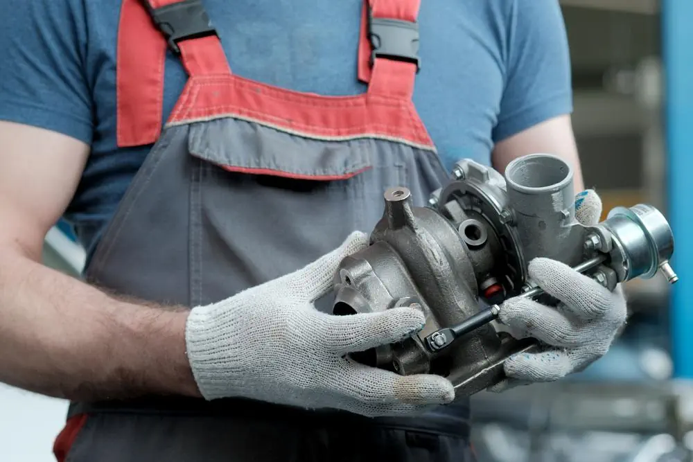 Ein Automechaniker hält einen neuen Turbolader in den Händen.